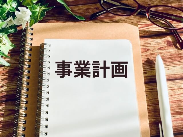 木製テーブル上の白い事業計画ノート