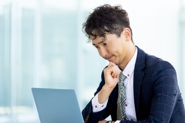 考え込むスーツ姿の男性とパソコン